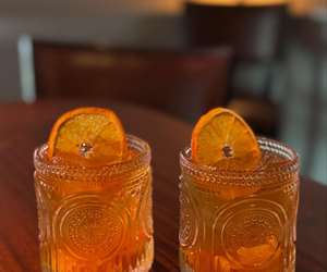 two cocktails with orange garnishes