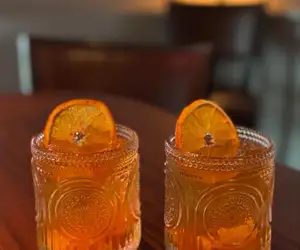 two cocktails with orange garnishes